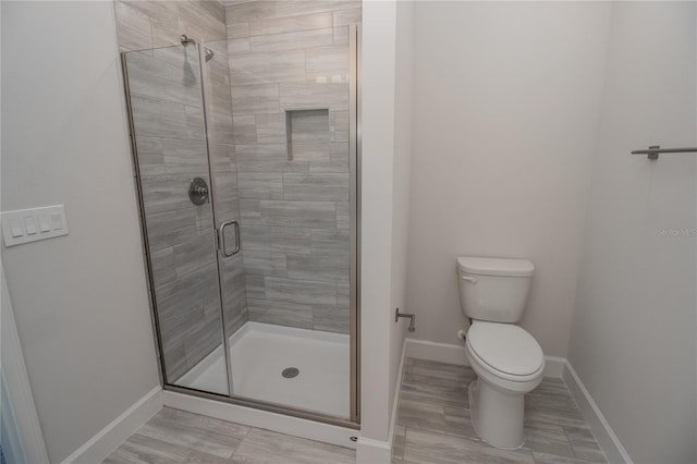 bathroom featuring a shower with door and toilet