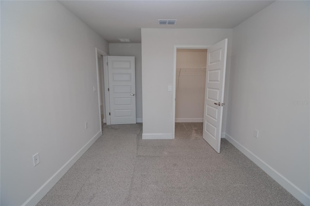 unfurnished bedroom featuring a walk in closet, a closet, and carpet floors