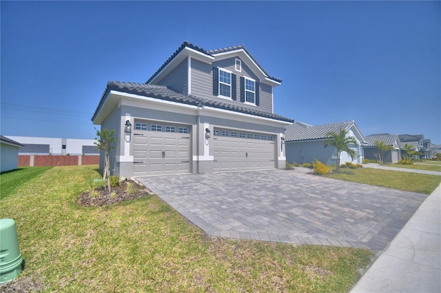 view of front facade featuring a tile roof, stucco siding, decorative driveway, a front yard, and a garage