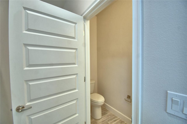 bathroom featuring toilet, baseboards, and wood finished floors
