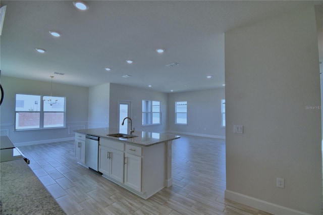 kitchen featuring light stone counters, a sink, white cabinetry, dishwasher, and open floor plan