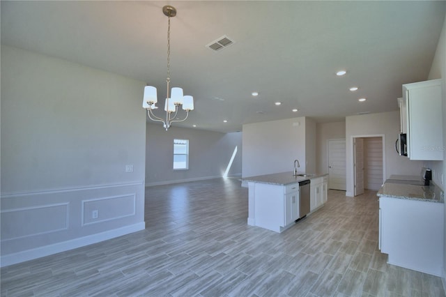 kitchen featuring a sink, white cabinetry, appliances with stainless steel finishes, a kitchen island with sink, and visible vents