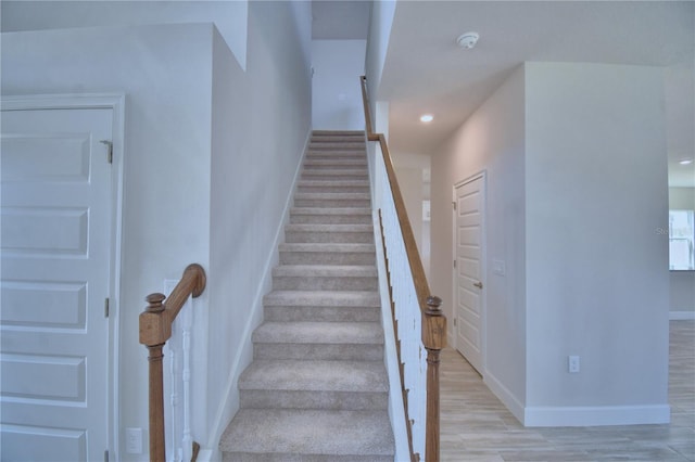 stairway with baseboards, wood finished floors, and recessed lighting