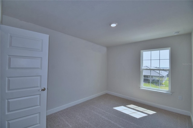 carpeted spare room featuring baseboards