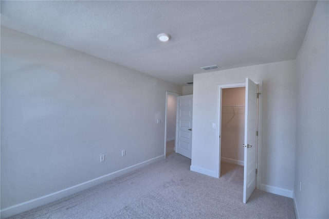 unfurnished bedroom featuring a closet, a spacious closet, baseboards, visible vents, and carpet