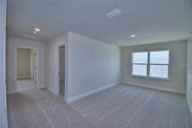 empty room featuring recessed lighting, light carpet, baseboards, and visible vents