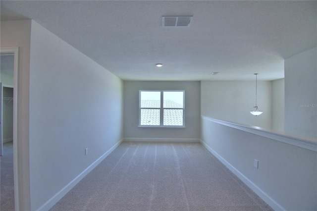spare room with baseboards, visible vents, and light colored carpet