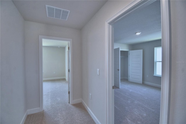 corridor with baseboards, visible vents, and carpet flooring