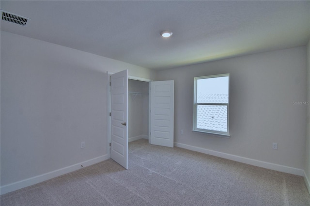 unfurnished bedroom with baseboards, carpet flooring, visible vents, and a closet
