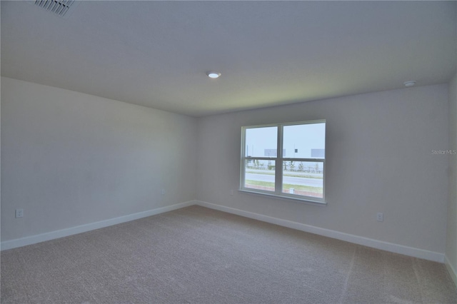 empty room with baseboards, visible vents, and light carpet