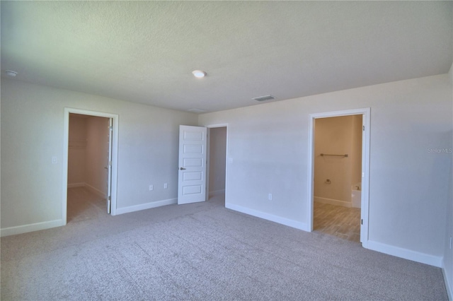 unfurnished bedroom featuring baseboards, visible vents, and a walk in closet
