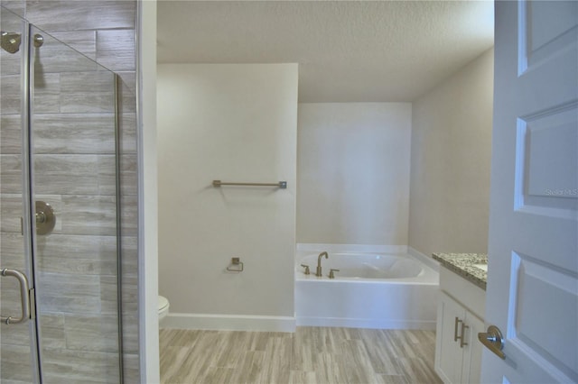 bathroom featuring a bath, a textured ceiling, wood finished floors, vanity, and a stall shower