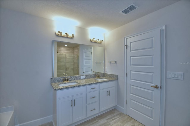 bathroom featuring double vanity, a sink, a stall shower, and visible vents