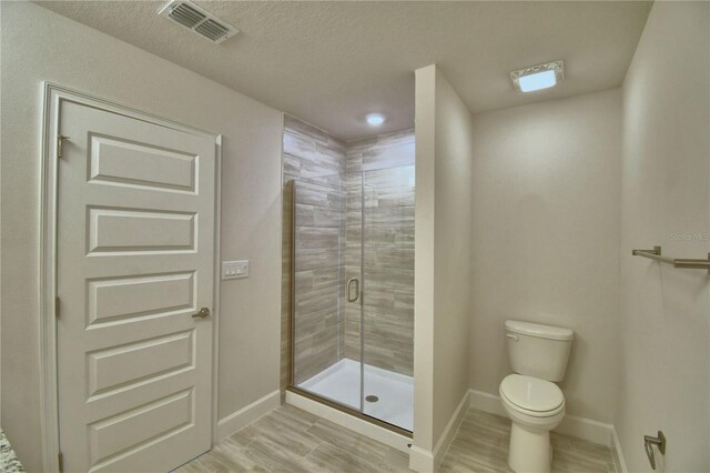 bathroom featuring toilet, a shower stall, wood finished floors, baseboards, and visible vents