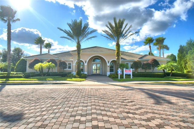 mediterranean / spanish-style home with stucco siding, a tiled roof, and french doors