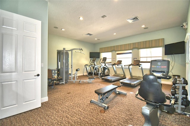 workout area with baseboards, a textured ceiling, visible vents, and recessed lighting