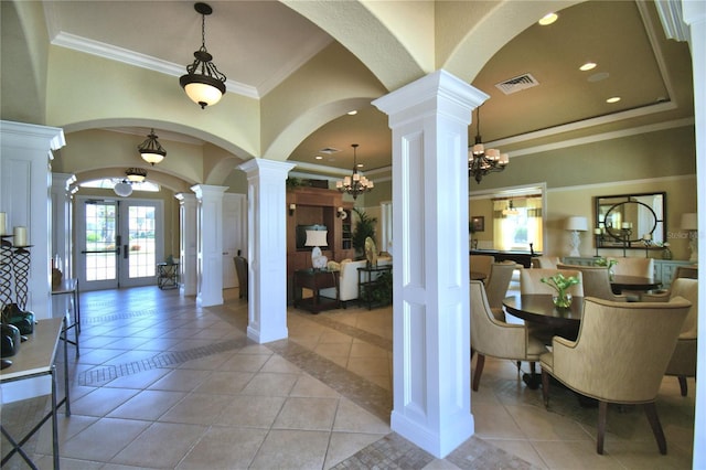 foyer entrance with decorative columns, a notable chandelier, light tile patterned floors, visible vents, and arched walkways