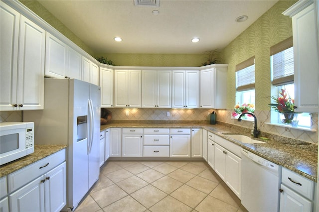 kitchen with light tile patterned flooring, a sink, white appliances, wallpapered walls, and white cabinets