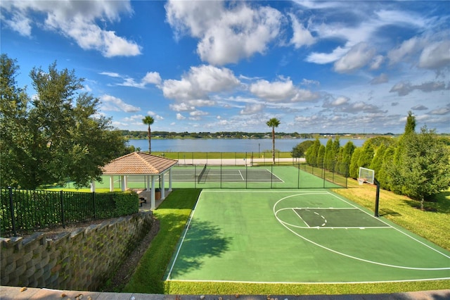 view of basketball court with community basketball court, a water view, fence, and a tennis court