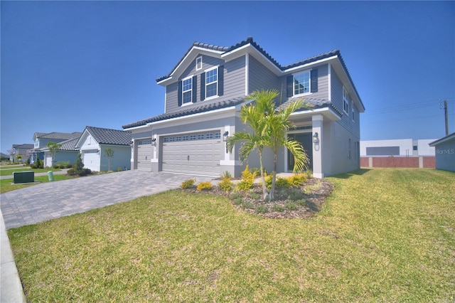 traditional-style home with an attached garage, a front lawn, and decorative driveway