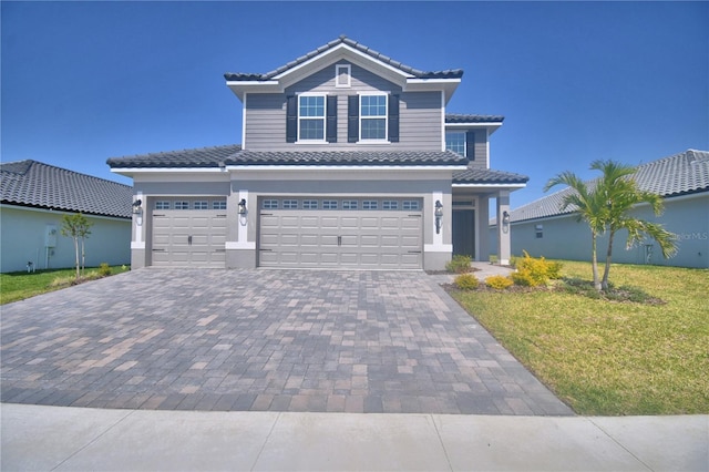 view of front of home with a front lawn, a tile roof, decorative driveway, and a garage