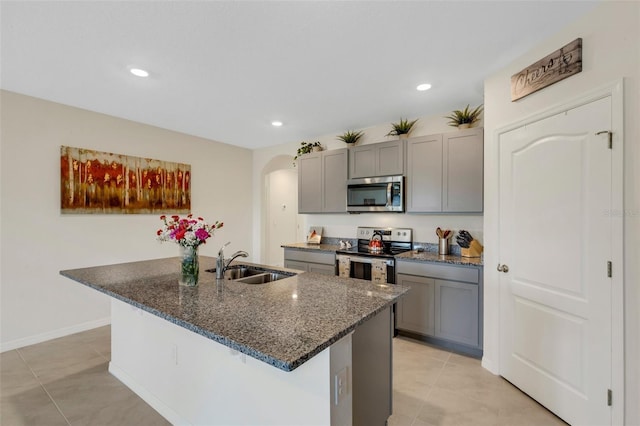 kitchen with arched walkways, appliances with stainless steel finishes, gray cabinets, and a sink