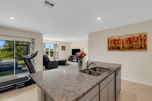 kitchen with a sink, visible vents, open floor plan, stainless steel dishwasher, and light stone countertops