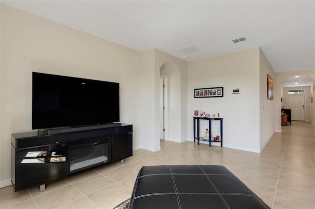 living area with arched walkways, visible vents, baseboards, and light tile patterned floors