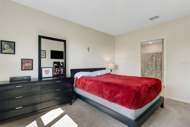 bedroom featuring light carpet, ensuite bath, baseboards, and visible vents