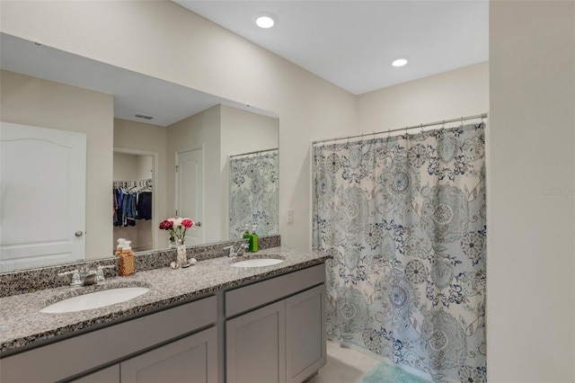 full bathroom featuring visible vents, a sink, a spacious closet, and double vanity