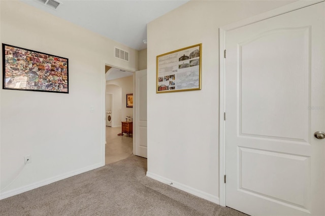 interior space featuring light carpet, baseboards, visible vents, and arched walkways