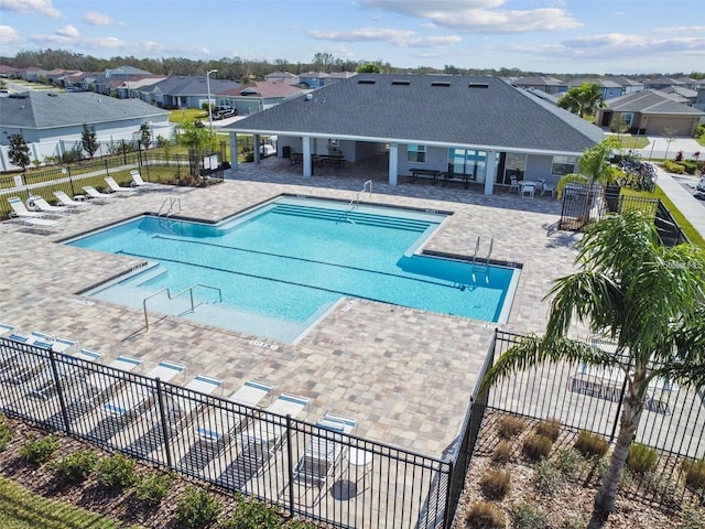 community pool with a residential view, a patio area, and fence