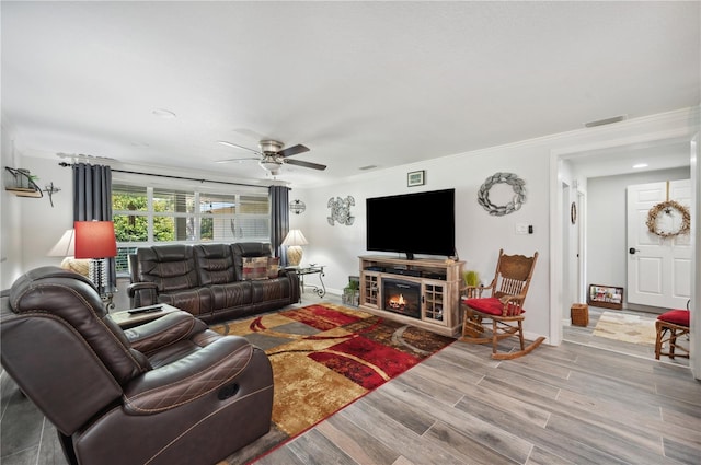 living room with ceiling fan, light wood-type flooring, and crown molding