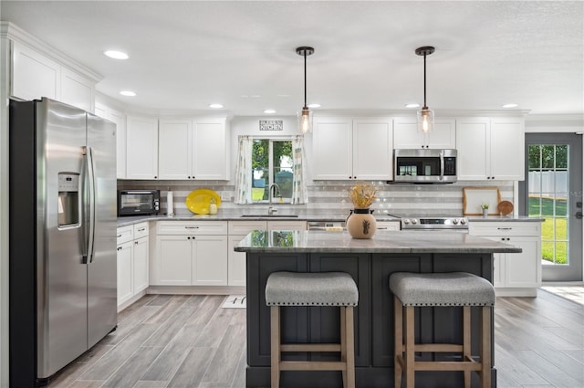 kitchen featuring sink, a center island, stainless steel appliances, pendant lighting, and a breakfast bar area