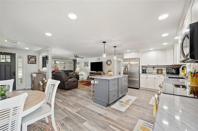 kitchen with gray cabinetry, stainless steel appliances, ceiling fan, decorative light fixtures, and white cabinetry