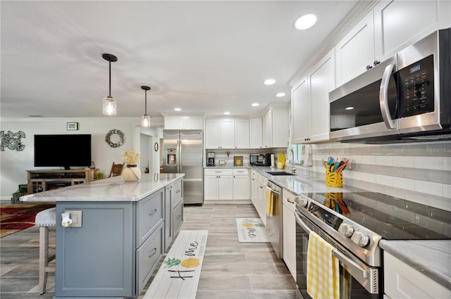 kitchen featuring a center island, gray cabinets, a kitchen bar, white cabinetry, and stainless steel appliances