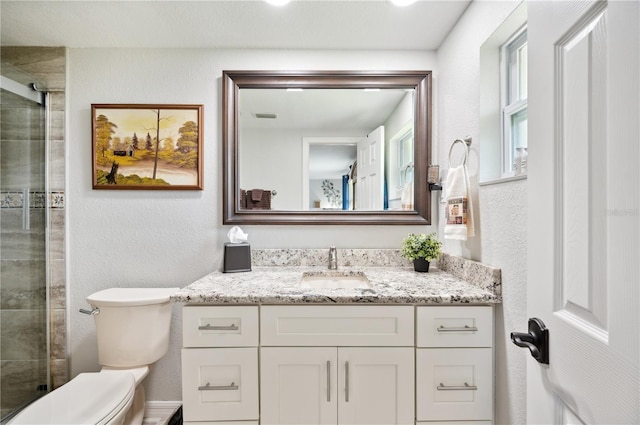 bathroom with vanity, toilet, and a shower with door