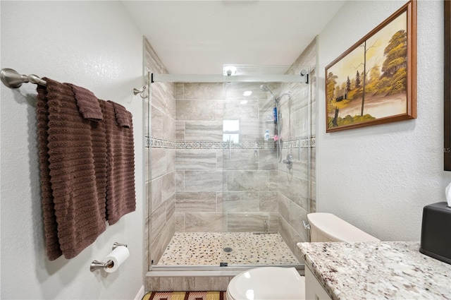 bathroom with vanity, toilet, and a shower with door