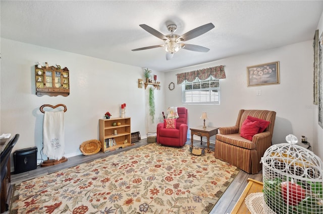 living area featuring ceiling fan, wood-type flooring, and a textured ceiling