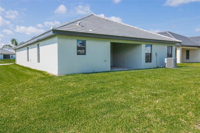 rear view of house with central AC unit and a lawn