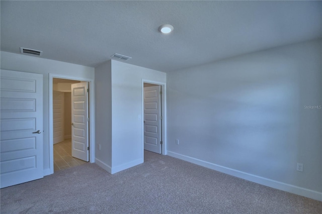 unfurnished bedroom with carpet floors, visible vents, and baseboards