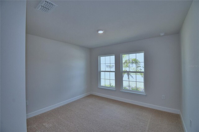 empty room with carpet floors, visible vents, and baseboards