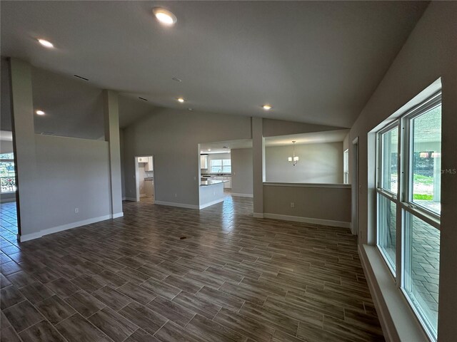 spare room featuring plenty of natural light, dark hardwood / wood-style floors, and vaulted ceiling