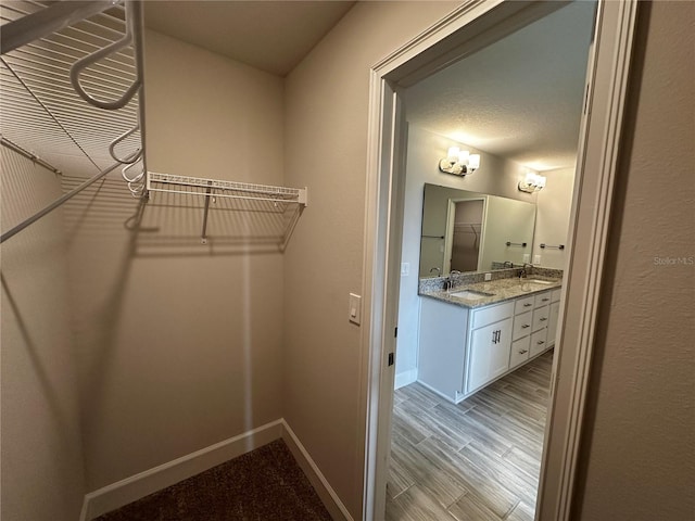 walk in closet with sink and light wood-type flooring