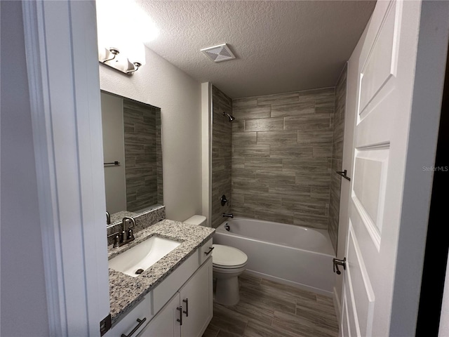 full bathroom with a textured ceiling, toilet, hardwood / wood-style flooring, vanity, and tiled shower / bath