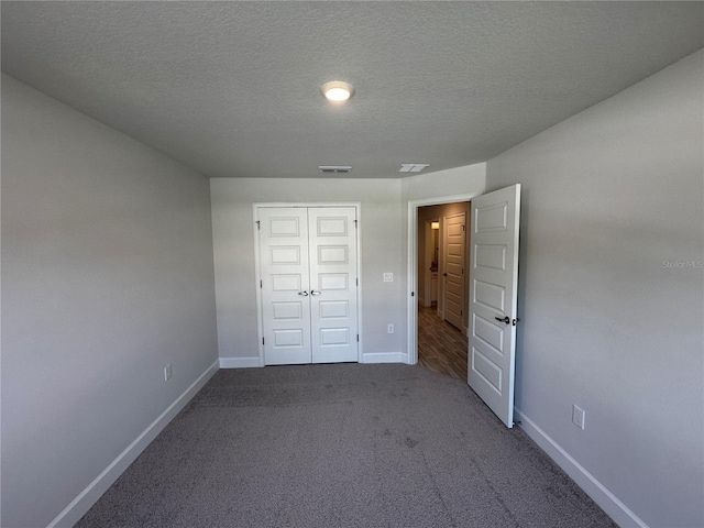 unfurnished bedroom featuring carpet flooring, a textured ceiling, and a closet