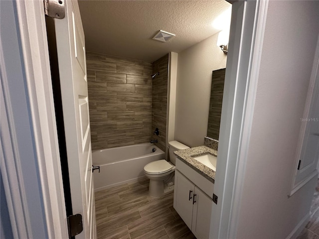 full bathroom with tiled shower / bath combo, hardwood / wood-style floors, a textured ceiling, toilet, and vanity