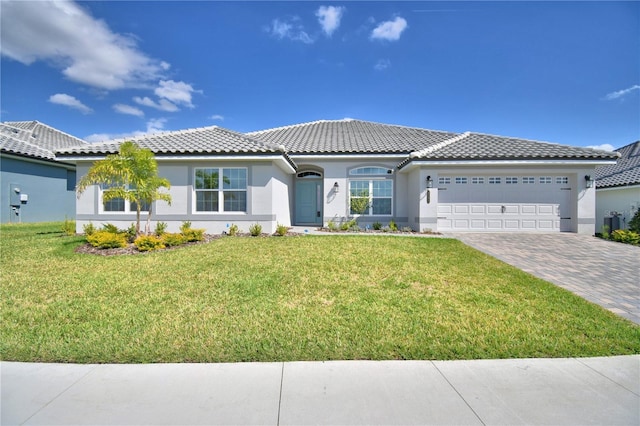 view of front of property with a tile roof, an attached garage, decorative driveway, a front lawn, and stucco siding