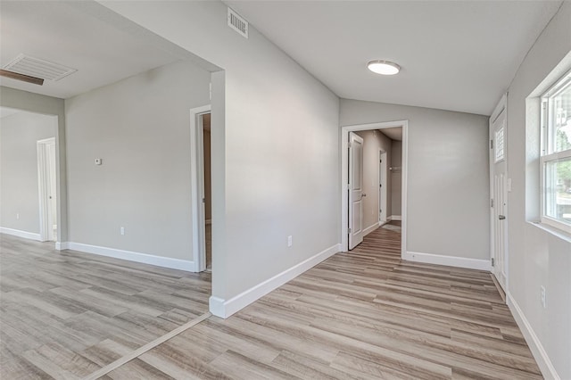 spare room featuring light wood-type flooring and vaulted ceiling