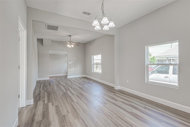 empty room featuring ceiling fan with notable chandelier and light hardwood / wood-style flooring